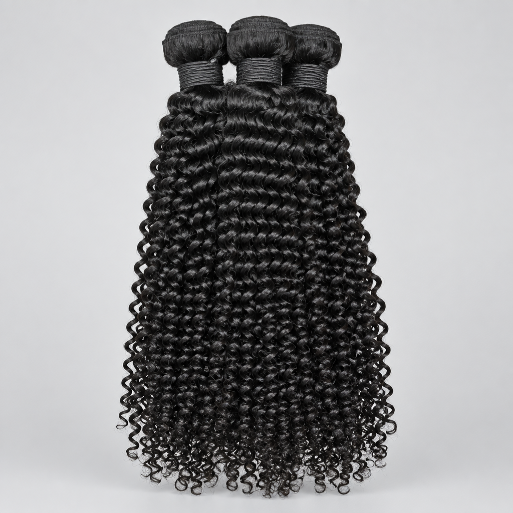 Three bundles of black curly hair extensions held up by a hand, featuring tight, defined deep waves with a glossy finish, set against a background of green houseplants and an indoor office space.